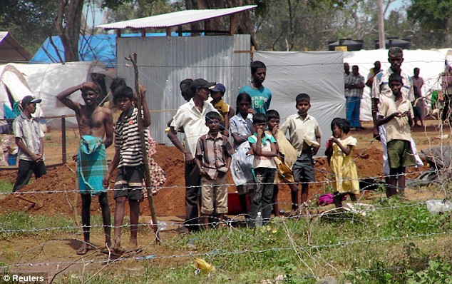 Daily Mail May 25, 2009 Victims of war: Tamil civilians stand behind a barbed-wire fence as they watch U.N. Secretary-General Ban Ki-moon tour their refugee camp