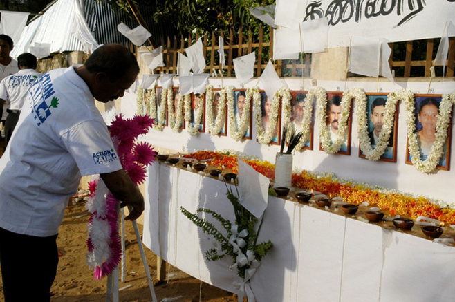 A member of the French aid group ACF places a wreath in front of the photographs of his slain colleagues at their memorial in Batticaloa