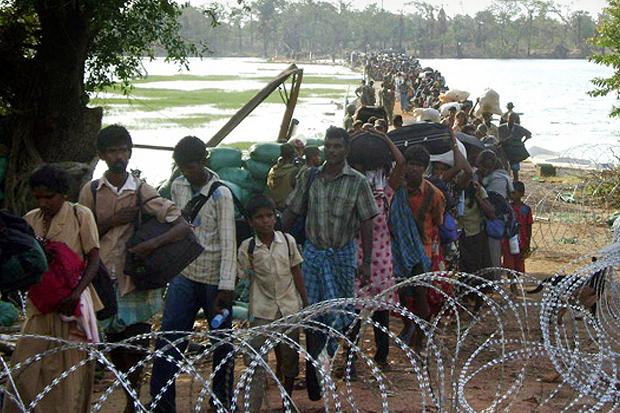 Civilians walking across a lagoon from inside the “No Fire Zone” where government troops have the Tamil Tiger rebels surrounded