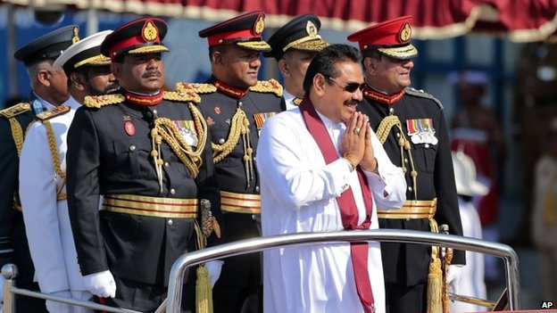 Sri Lankan President Mahinda Rajapaksa, in white, rides on a vehicle with security forces commanders as he greets people during a Victory Day parade in Matara, 18 May 2014