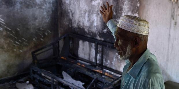 A Sri Lankan resident surveys the damage to a charred Muslim-owned home following clashes between Muslims and an extremist Buddhist group in the town of Alutgama.