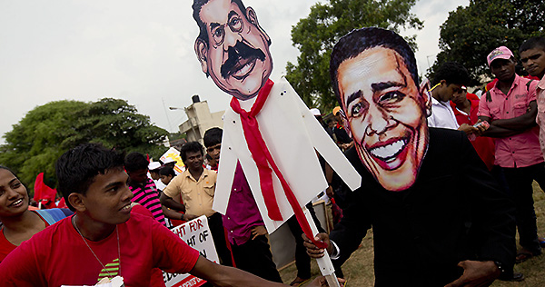 A protestor wears a mask of U.S. President Barack Obama, while holding a puppet of former Sri Lankan President Mahinda Rajapaksa during a rally in 2013. Pic: AP.